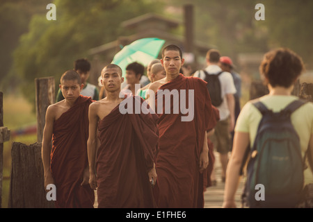 I giovani monaci buddisti a piedi passato turisti sul popolare U Bein ponte di legno in Myanmar. Foto Stock