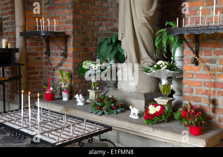 Candele di fronte ad una statua di Maria in una piccola cappella Foto Stock