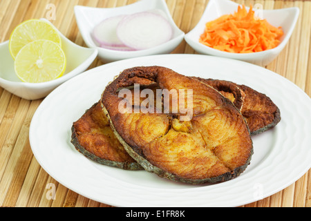 Macro di deliziose, coperti fritto, veggente incrostato/sgombro filetti di pesce serviti con carote grattugiate, materie anelli di cipolla e limone. Foto Stock