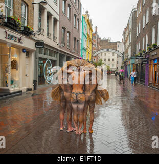 Carnaby Street, Londra UK. Il 3 giugno 2014. Una maggiore vita lion realizzato da dipinte a mano e figure umane appare in Carnaby Street per un solo mattina al marchio della Società Zoologica di Londra impostazione shop in numero 15 della famosa strada come parte di ZSL's Lions400 campagna - un ambizioso per la raccolta di fondi pubblici progetto ideato per sollevare £5.7m per la conservazione di una specie minacciata Asian lion Foto Stock