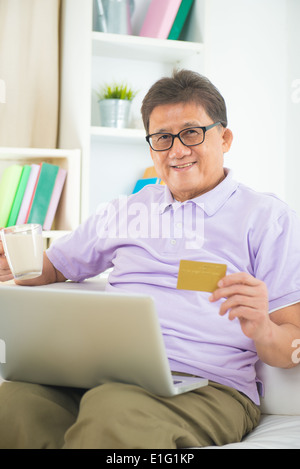 Senior maschio asiatici per lo shopping online da casa Foto Stock