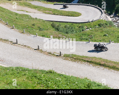 I turisti in moto rigido fino la pietra ciottoli strada pavimentata ("Tremola') sullo storico passo di montagna del San Gottardo in Svizzera. Foto Stock