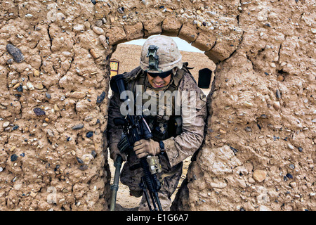 US Marine LCpl. Giuseppe Guthrie III spreme attraverso una apertura di fango in un composto abbandonate durante una pattuglia di ricognizione Maggio 15, 2014 vicino a Patrol Base Boldak nella provincia di Helmand, Afghanistan. Foto Stock