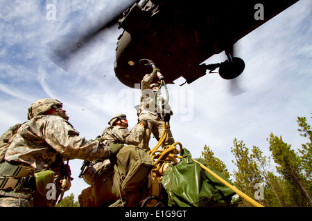 Stati Uniti Paracadutisti dell'esercito imbracare il carico di un M-119A2 105 mm obice a UH-60M Blackhawk elicottero durante air assault formazione a Fo Foto Stock