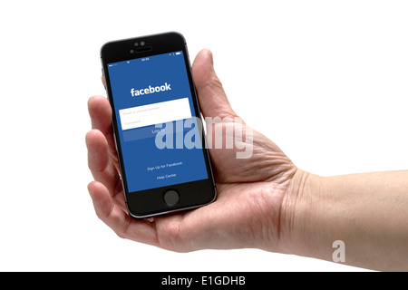 Una mano Holden un iPhone con Facebook login page. Foto Stock