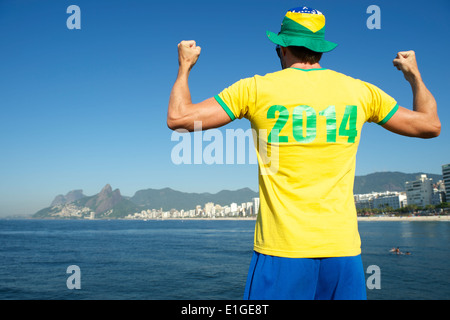 Uomo brasiliano nel 2014 shirt in colori brasiliano celebrando in tropicale sulla spiaggia di Ipanema di Rio de Janeiro Foto Stock