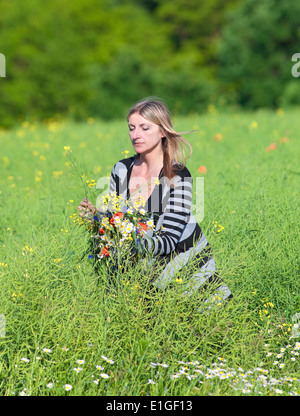 La donna la raccolta di fiori selvatici sul prato in primavera Foto Stock