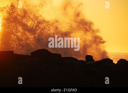 Onde al tramonto contro il molo sud del Rogue River vicino alla spiaggia di oro o Foto Stock