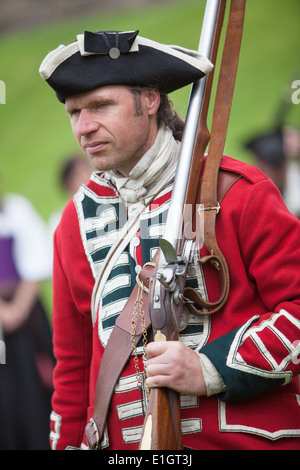 Un soldato vestito in tradizionali del XVII secolo Esercito Inglese Redcoat uniforme con spallamento di tenuta di un moschetto flintlock. Foto Stock