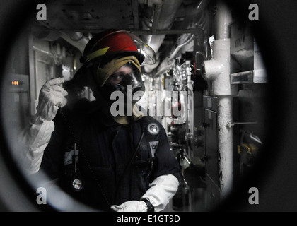 Stati Uniti Navy Engineman 3° di classe Charlie Shroba relè un messaggio dalla scena di un incendio simulato di marinai nel riparare locke Foto Stock