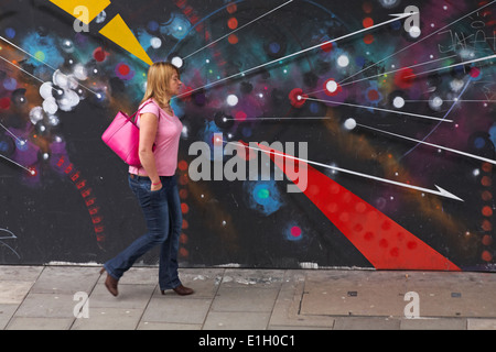 Donna oltrepassando la street art graffiti a Bristol Foto Stock