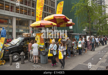 Linea di persone fino a mangiare al immensamente popolare Halal ragazzi cibo Carrello a 53A SAN & 6th Ave. in midtown Manhattan. Foto Stock