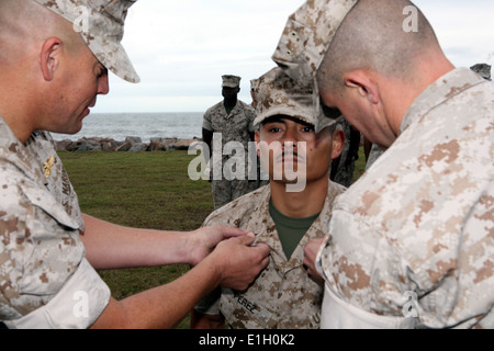 Stati Uniti Marine Corps Staff Sgt. Tomas Perez ha nuovi freccette segnato per la sua uniforme da Capt. Scott Benninghoff, un responsabile della logistica Foto Stock