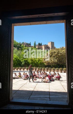 I bambini della scuola di ascoltare il loro insegnante su una visita di istruzione ai siti storici di Granada, Spagna Foto Stock