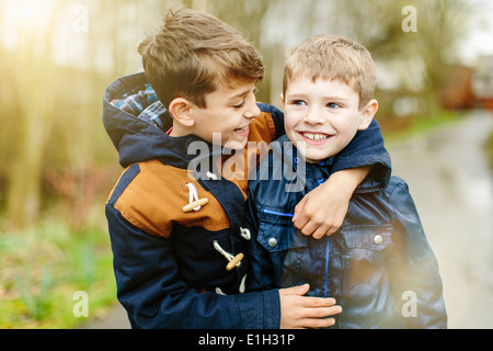 Fratelli abbracciando all'aperto Foto Stock