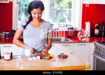 Giovane donna affettamento fragola in cucina Foto Stock