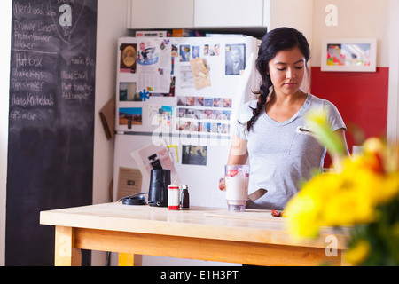 Giovane donna miscelazione di frutti in cucina Foto Stock