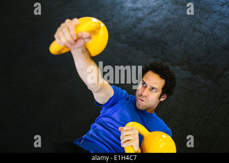 L'uomo sul retro kettlebells di sollevamento Foto Stock