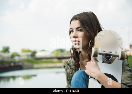 Giovane donna azienda skateboard Foto Stock