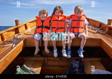 Tre bambini seduti in barca Foto Stock