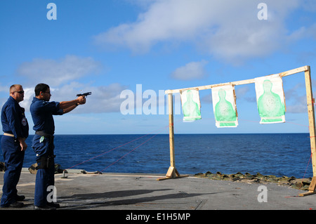 Stati Uniti Operazioni navali specialista di terza classe Marcelo Martis, diritto, incendi un M9 Pistola Beretta come Chief Master-at-Arms Jeffrey Bar Foto Stock