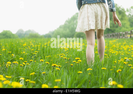 Vita scende vista posteriore della giovane donna passeggiando nel campo Foto Stock