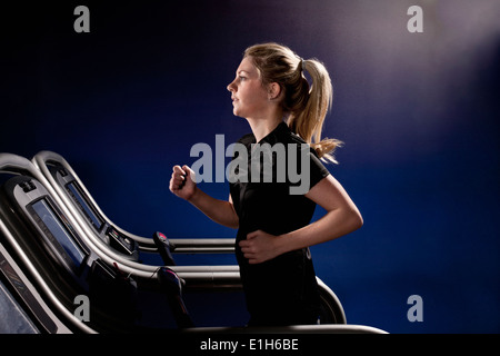 Giovane donna in esecuzione sul tapis roulant in palestra nel centro di altitudine Foto Stock