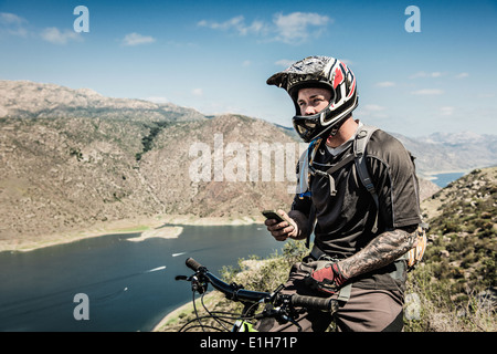Downhill mountain biker utilizza lo smartphone Foto Stock