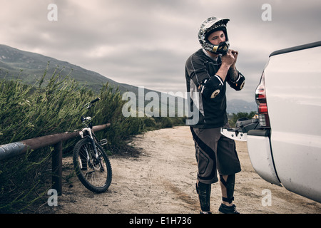 Downhill mountain biker mettendo sul casco Foto Stock