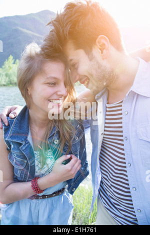 Coppia giovane con le braccia intorno a ogni altro ridere Foto Stock