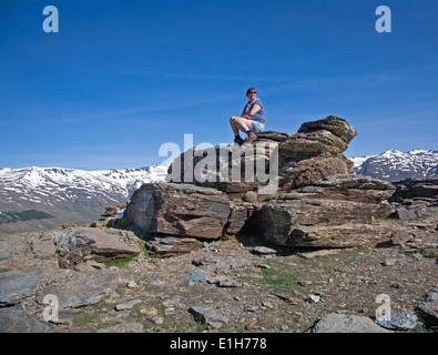 Donna seduta sul promontorio roccioso nelle montagne della Sierra Nevada in alta Alpujarras, vicino a Capileira, provincia di Granada, Spagna. Foto Stock