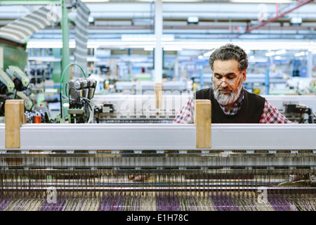 Maschio operaio di fabbrica sulla macchina di tessitura di lana mill Foto Stock