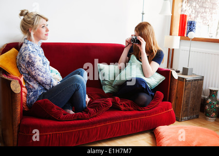 Giovane donna seduta su un divano, tenendo fotografia Foto Stock