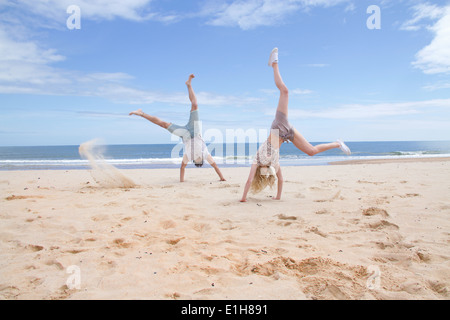 Coppia giovane facendo le verticali sulla spiaggia Foto Stock