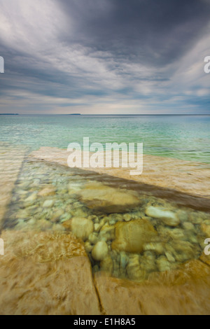 Interessanti formazioni di roccia sotto le acque cristalline con estrema nuvole temporalesche overhead. Bruce Peninsula NP, Ontario, Canada Foto Stock