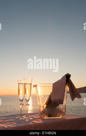 Champagne flauti e benna contro il tramonto Foto Stock