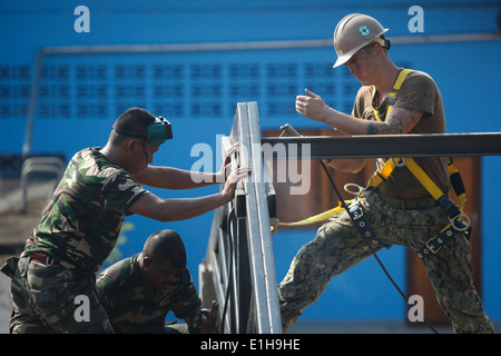 Marinai thailandese e un U.S. Sailor assegnato alla Naval Mobile Battaglione di costruzione 40 saldare una travatura a su un edificio polifunzionale essere Foto Stock