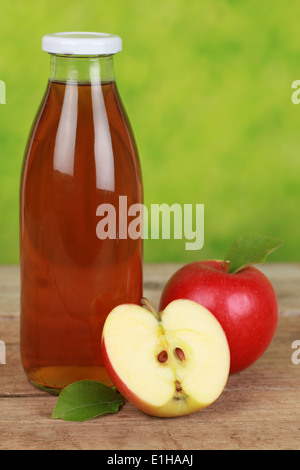 Il succo di mela in una bottiglia decorata con mele mature Foto Stock