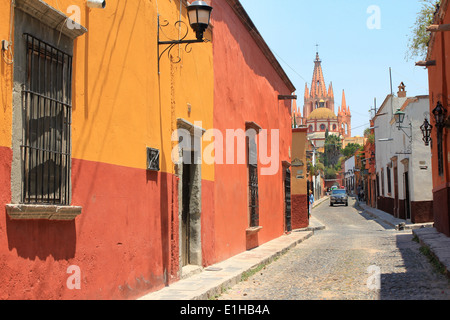 Colorati edifici coloniali che costeggiano una strada che conduce verso il retro della chiesa di la Parroquia a San Miguel de Allende, Guanajuato, Messico Foto Stock