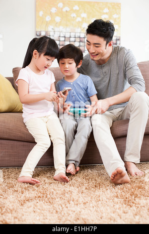 La famiglia felice la riproduzione di appiglio video gioco in divano Foto Stock