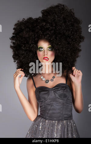 Stravaganza. Eccentrica donna emotiva in Frizzy Fancy Parrucca con capelli intrecciati Foto Stock