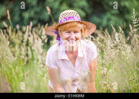 Positività. Felice Senior contadina in Prato sorridente. Coppia Gentile Signora nel cofano motore Foto Stock