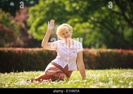 La maturità. Unione i capelli bianchi donna seduta su erba e divertirsi Foto Stock
