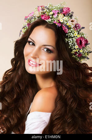 Genuine giovane donna con flusso di capelli sani e ghirlanda di fiori Foto Stock