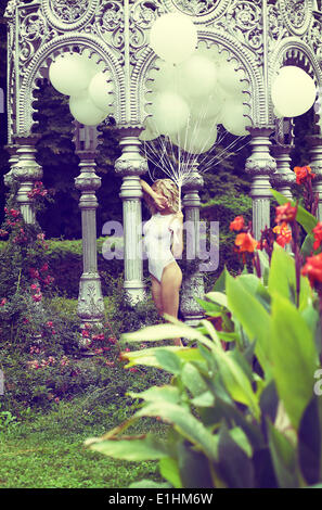 Sentimento. Bella bionda rilassato trattenere aria palloncini in giardino Foto Stock