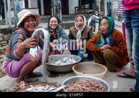 Alcune donne scherzo mentre la vendita del pesce al dock in un villaggio di pescatori ad Hoi An Foto Stock