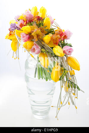Fiorai - fiore coloratissimo bouquet centrotavola disposizione in vaso trasparente isolato su sfondo bianco Foto Stock