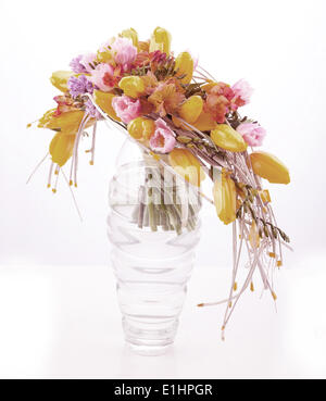 Fiori colorati in disposizione di configurazione nel vaso di vetro con tulipani gialli isolato su bianco Foto Stock