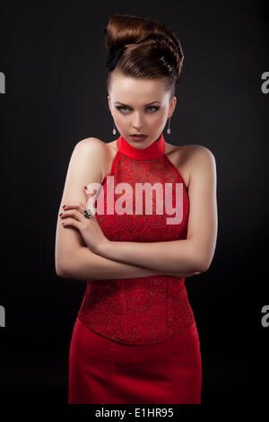 Strict bella donna d'affari in abito rosso isolato su sfondo nero Foto Stock