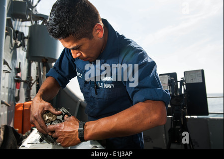 Da bombardieri marinaio compagno Daniel Hernandez, da San Antonio, esegue le operazioni di manutenzione su una parte di un 0,50 Caliber machine gun sulla ventola Foto Stock